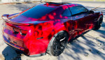 2013 Chevrolet Camaro ZL1 in red parked outdoors, showcasing its sleek design and custom black wheels.