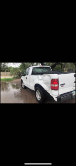 2006 Ford F150 XL with low mileage, showing rear damage and new tires parked outdoors.