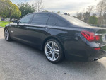 2015 BMW 750Li M Sport in Jet Black parked on street, showcasing sleek design and luxury features.