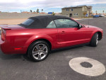 2008 Ford Mustang convertible in red, showcasing bodywork and roof features in excellent condition, parked on the street.