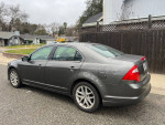 2010 Ford Fusion parked on a street, featuring new tires and a sleek gray exterior, ideal for comfortable long-distance drives.