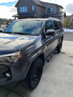 2023 Toyota 4Runner SR5 RWD parked, showcasing black wheels and features in front of a modern house.