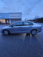 2006 Honda Civic in mint condition, gray exterior, parked with wet pavement, showcasing its sleek design.