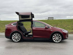 2016 Tesla Model X P90D in red with falcon wing doors open, showcasing spacious interior and sleek design