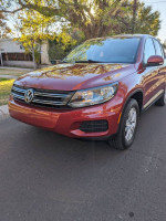 2013 Volkswagen Tiguan S in red, showcasing its excellent condition and low mileage, parked on a sunny street.