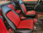 Interior view of a classic car with black and red leather seats, showcasing vintage design and craftsmanship.
